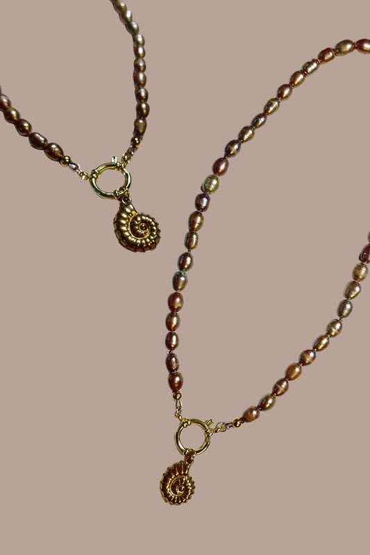 Collar de perlas con colgante de caracola, todo en acero inoxidable.