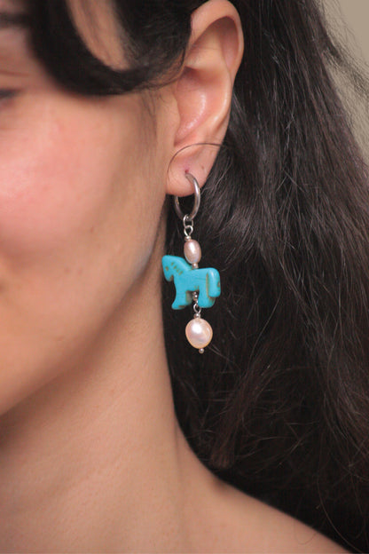 Pendientes artesanales de acero plateado y perlas que capturan la elegancia del año del caballo. 