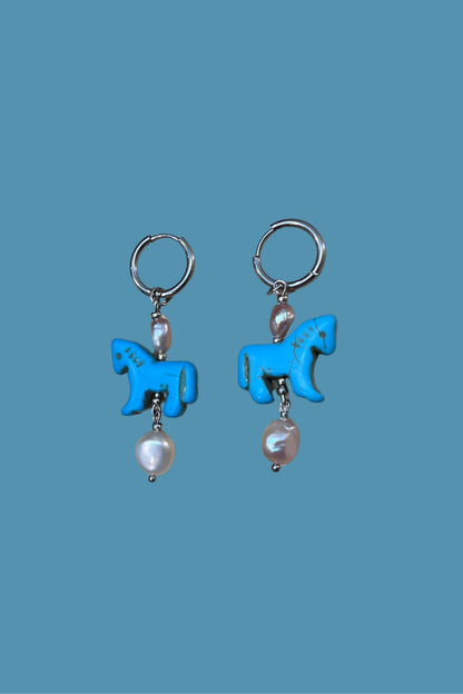 Pendientes artesanales de acero plateado y perlas que capturan la elegancia del año del caballo. 
