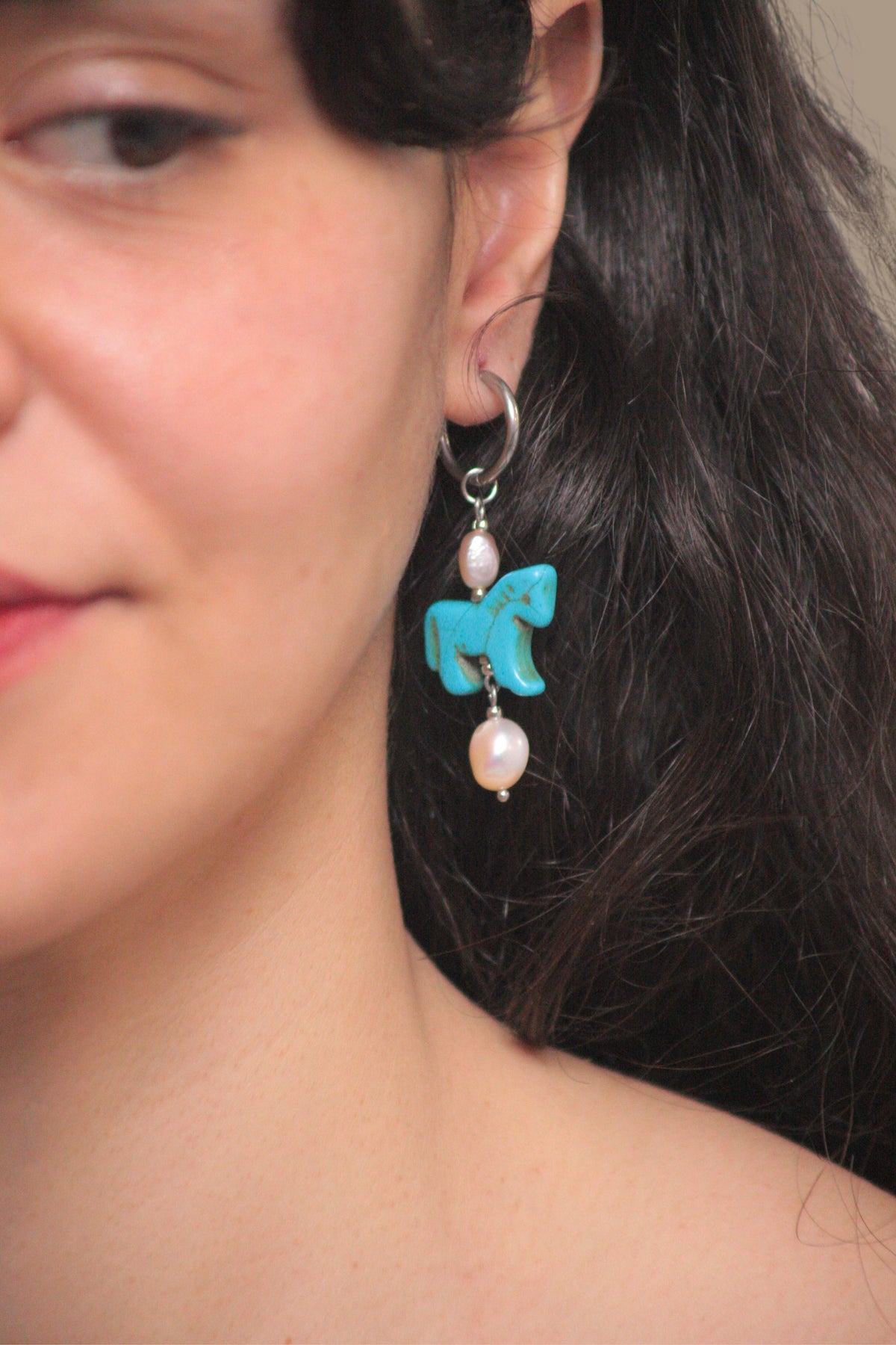 Pendientes artesanales de acero plateado y perlas que capturan la elegancia del año del caballo. 