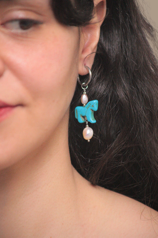 Pendientes artesanales de acero plateado y perlas que capturan la elegancia del año del caballo. 