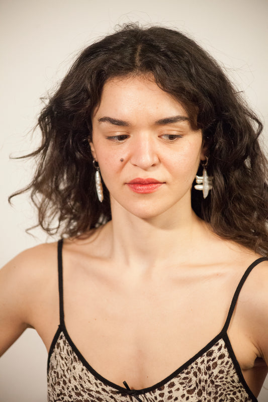 Mujer de pelo rizado con pendientes artesanales de perla natural con un diseño original y hechos a mano. 
